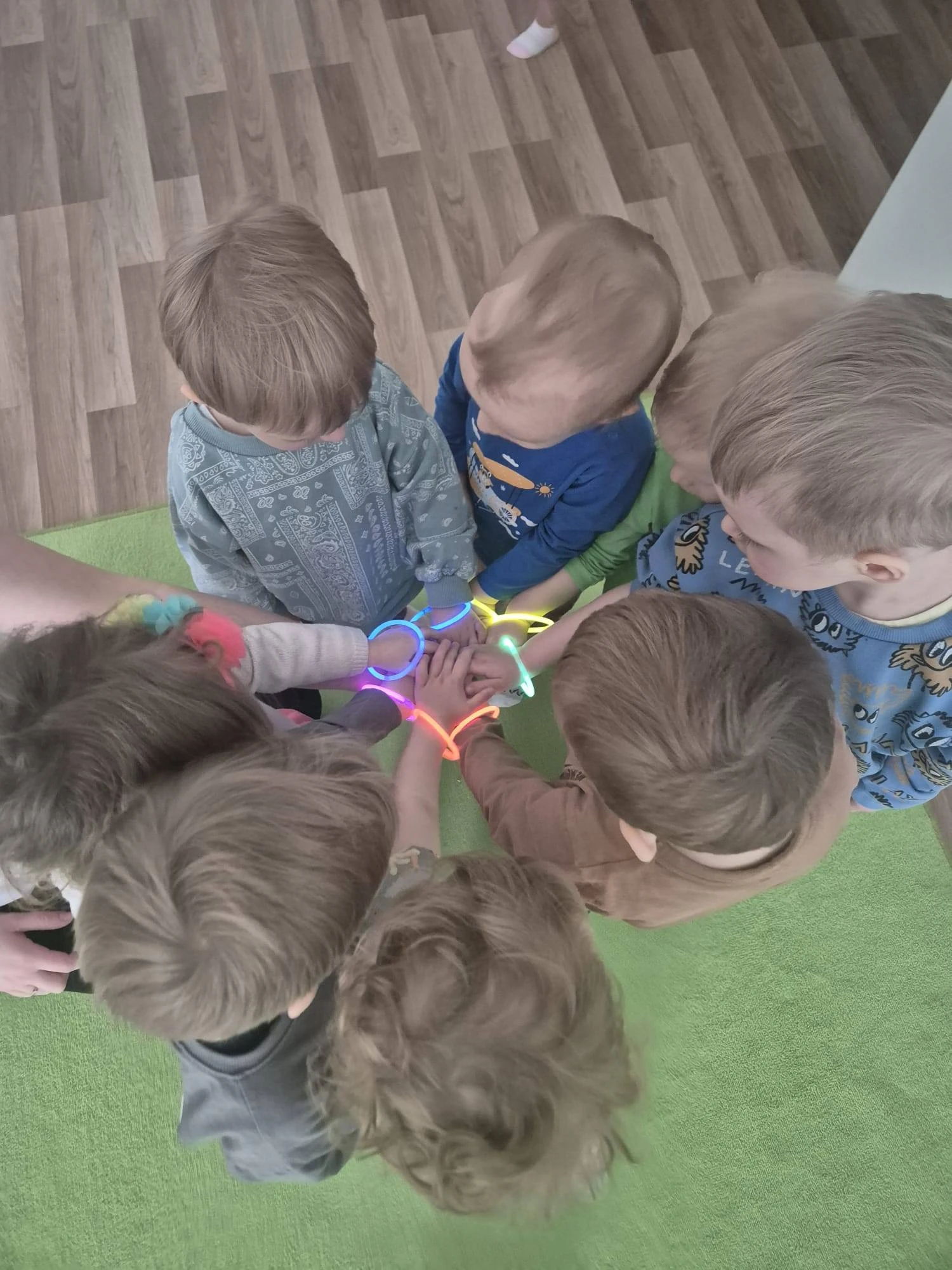 Dzieci w kręgu z neonowymi opaskami — magiczna chwila w żłobku